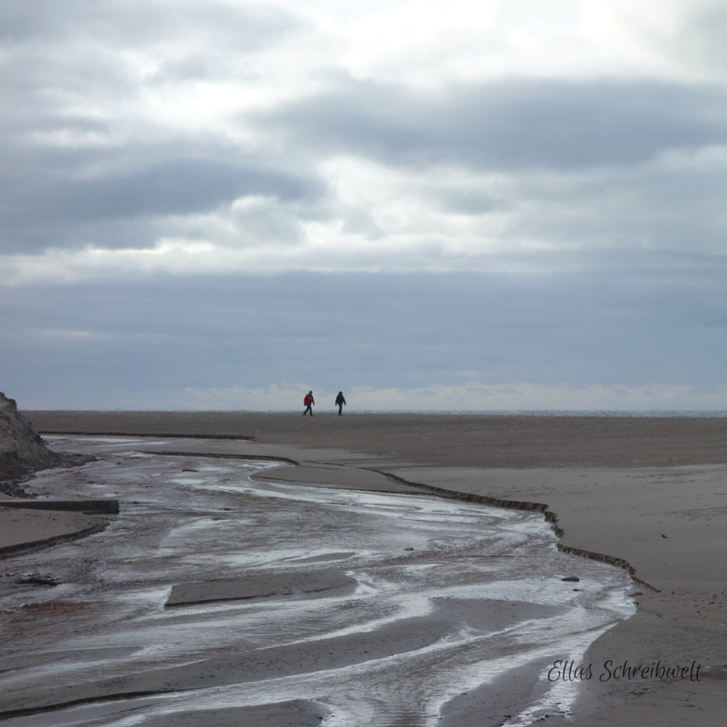 Ein Pärchen spaziert im Winter am Strand in Dänemark